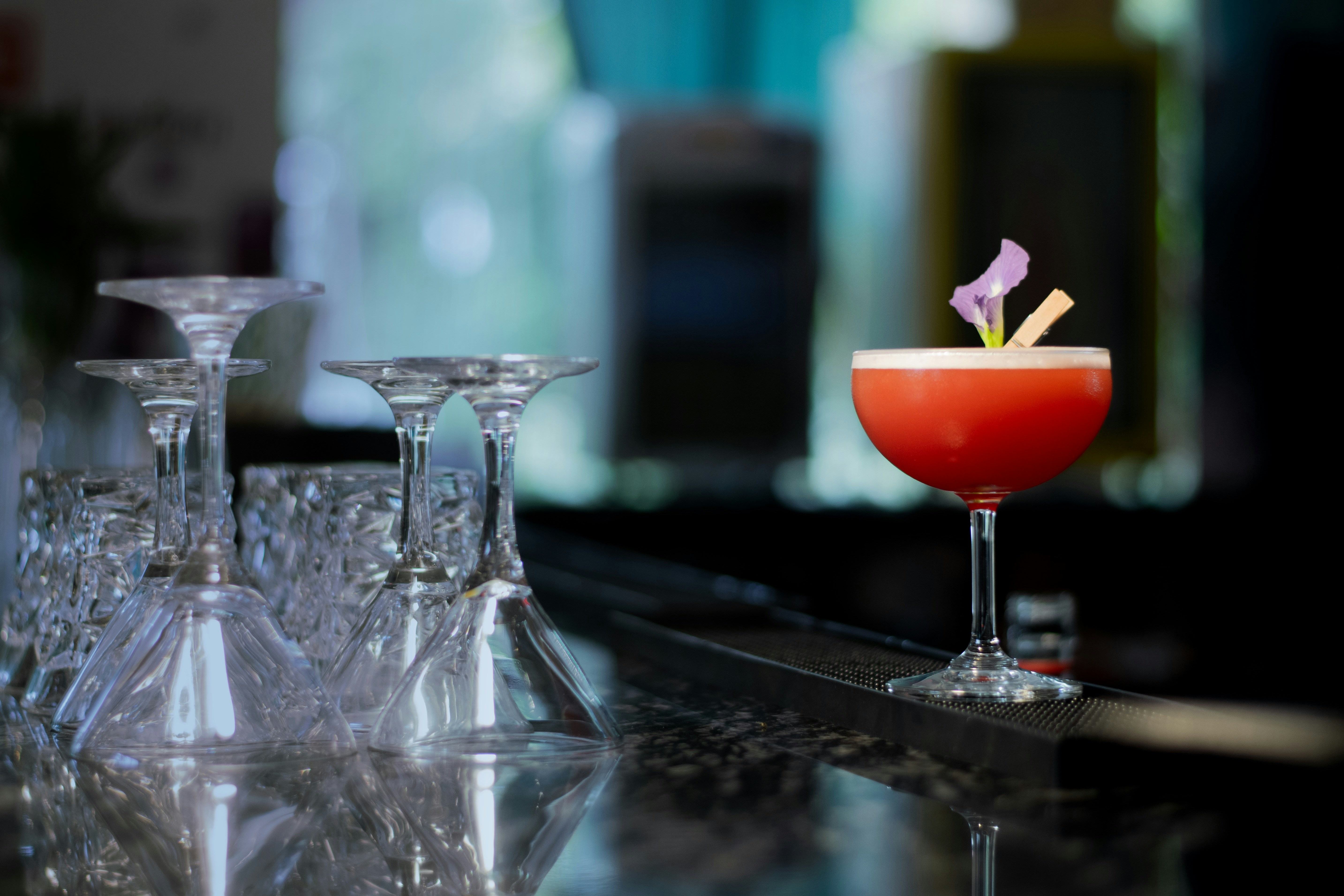 Coupe cocktail with blossom garnish on a reflective bar counter.